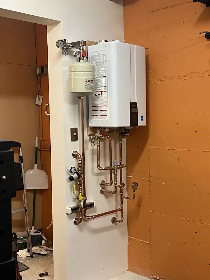 Plumbing technician inspecting water heater connections in Castleton